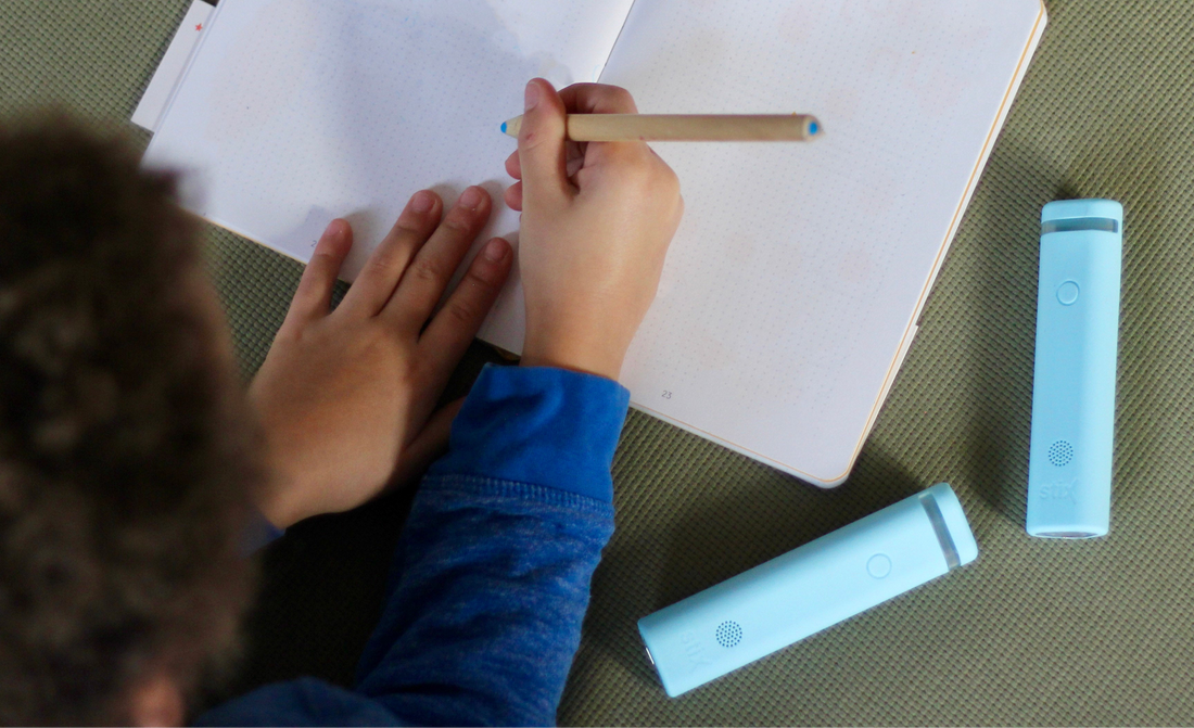 Child writing in their workbook whilst revising for exam season. How to beat exam anxiety with Stix.